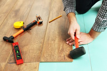 Carpenter worker installing laminate flooring in the room